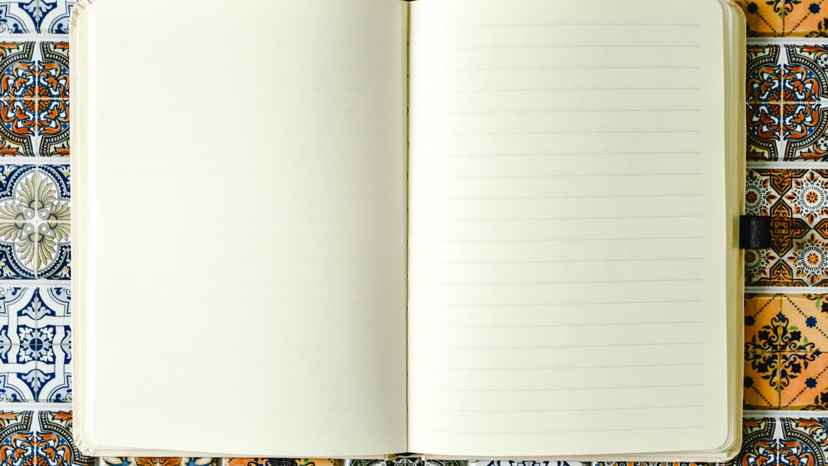 Blank lined notebook on a vibrant patterned tile background, perfect for creative use.